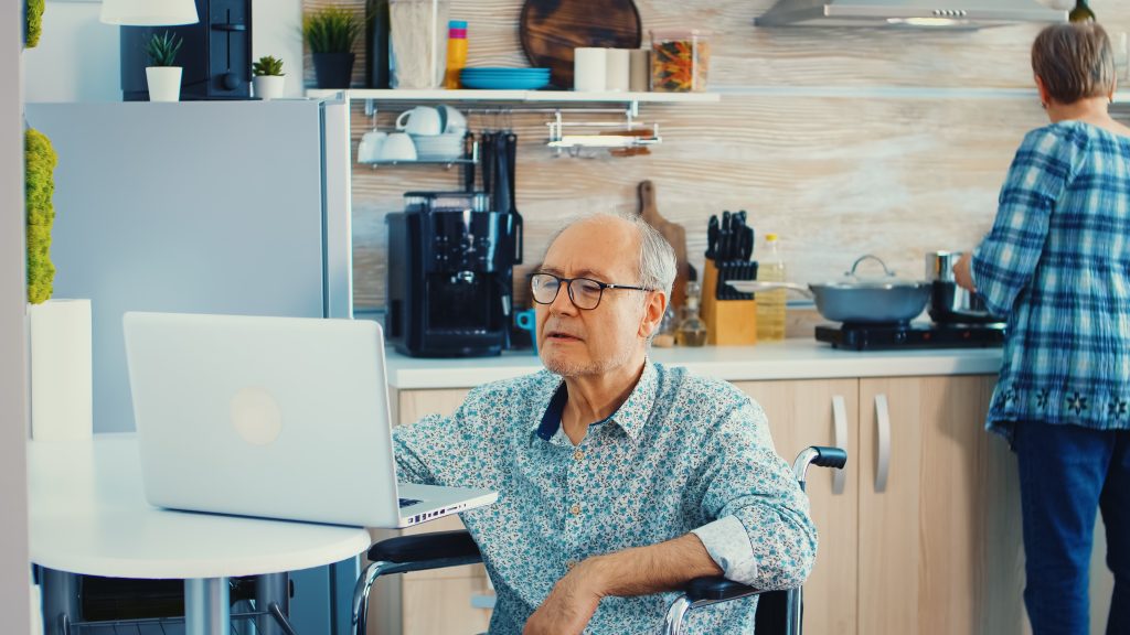 Elderly disabled person working on laptop